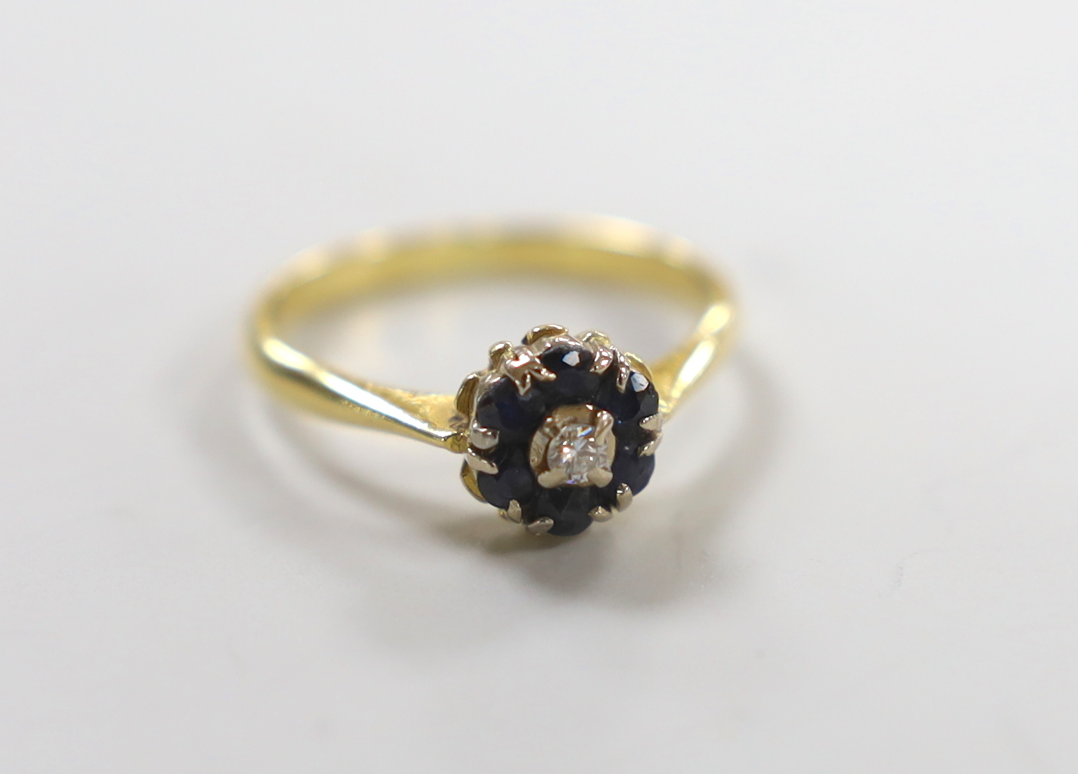 A modern yellow metal, sapphire and diamond cluster set ring, size M, gross weight 2.8 grams.